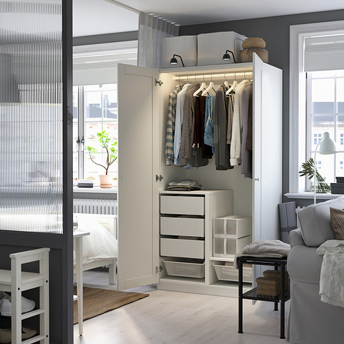Armario blanco moderno con espacio abierto, iluminado en el interior, cajones, entre dormitorio y sala de estar con silla, mesa, planta.