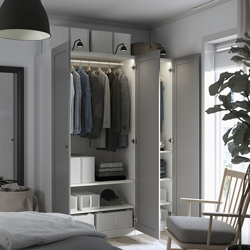Armario moderno con puertas abiertas, exhibiendo ropa y estantes. Las cajas de almacenamiento y una silla son visibles, con luces interiores que iluminan el contenido.