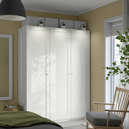 Dormitorio con gran armario PAX blanco, cama verde y silla de madera.