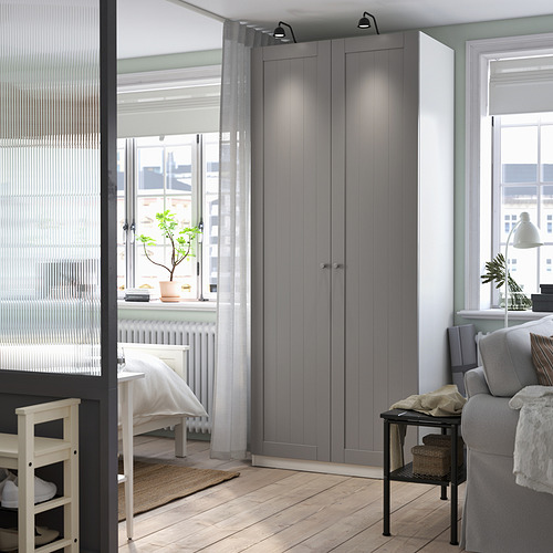 Modern bedroom with tall grey PAX wardrobe, desk, and grey couch.