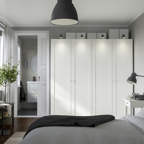 Dormitorio minimalista con armario PAX blanco, cama gris, suelo de madera y planta colgante.