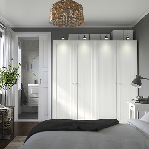 Dormitorio moderno con gran armario PAX, cama oscura, lámpara negra y baño pequeño.