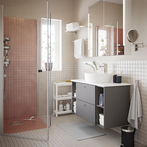 Baño moderno con paredes blancas, azulejos rosas, almacenamiento gris, espejo grande, lavabo, puerta de ducha de vidrio OPPEJEN.
