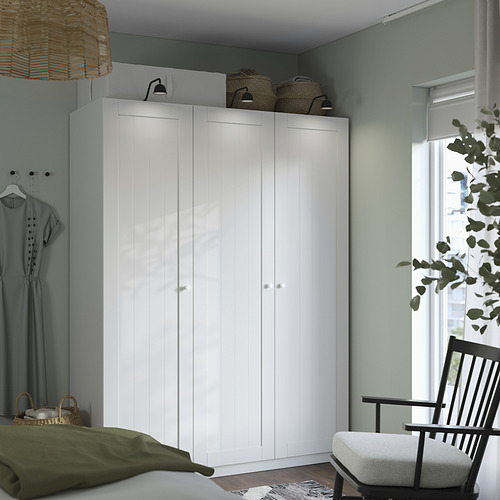 Armario blanco, silla negra, cama verde, cesta de mimbre, decoración.