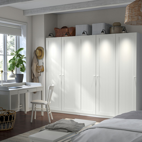 El armario PAX se mantiene alto junto al escritorio, pieza central con almacenamiento, bolsas en la parte superior, cajas en el interior, luminoso y moderno en una habitación acogedora.
