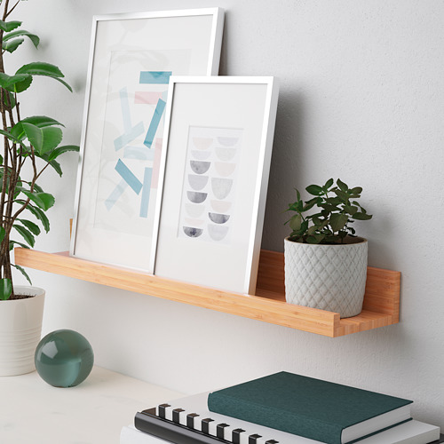 El estante de madera exhibe arte, plantas y libros, mostrando una configuración de decoración para el hogar ordenada y organizada.
