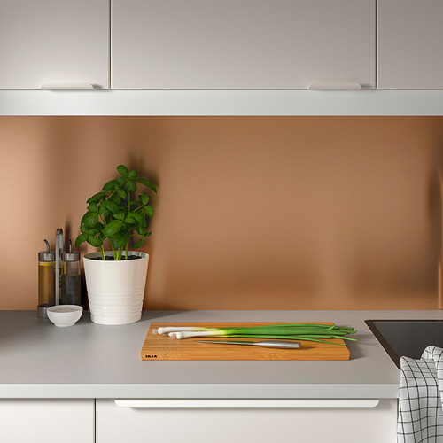 Cocina moderna con panel LYSEKIL. El mostrador tiene cebollas verdes, cuchillo, planta y tazón.