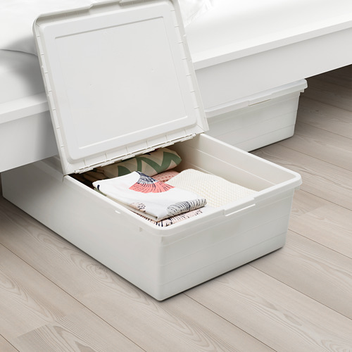 Dos cajas de almacenamiento blancas debajo de una cama. Una caja está abierta, revelando ropa cuidadosamente doblada. La tapa tiene una función de bloqueo y permite la circulación del aire.