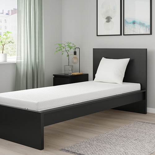 ÅBYGDA cama individual negra con colchón blanco, almohada, lámpara, planta, arte, suelos claros.