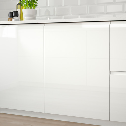Cocina moderna con armarios VOXTORP blancos de alto brillo, con tiradores integrados. Una planta en maceta y una botella descansan sobre la encimera.