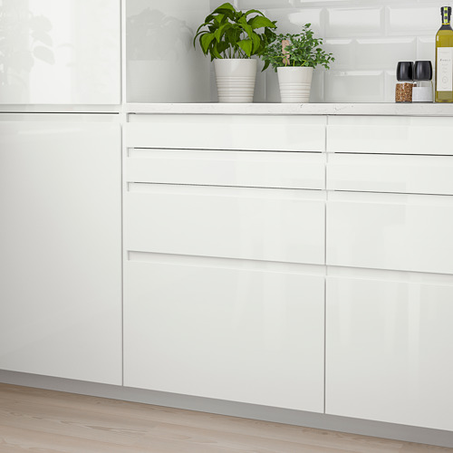 Modernos gabinetes de cocina blancos brillantes con un diseño elegante y manijas integradas, acentuados con pequeñas plantas en macetas y una botella en la encimera.