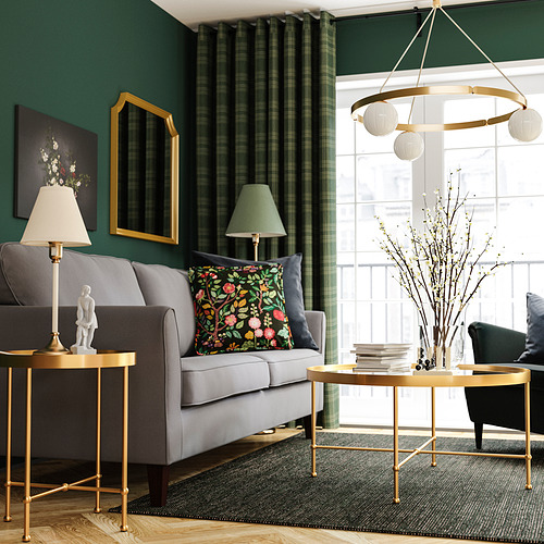 Elegante sala de estar con sofá gris, detalles dorados y cortinas verdes.