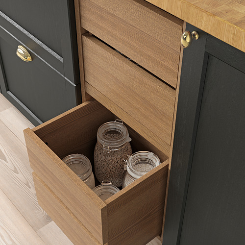 Cajón de cocina de madera con tirador de latón, parcialmente abierto, dejando al descubierto frascos de vidrio con el contenido a la vista.