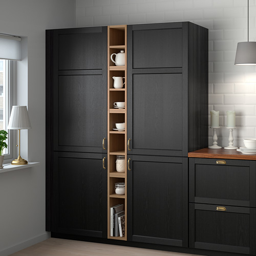 Mueble VADHOLMA negro con puerta abierta, que exhibe cerámica y libros cerca de una ventana.