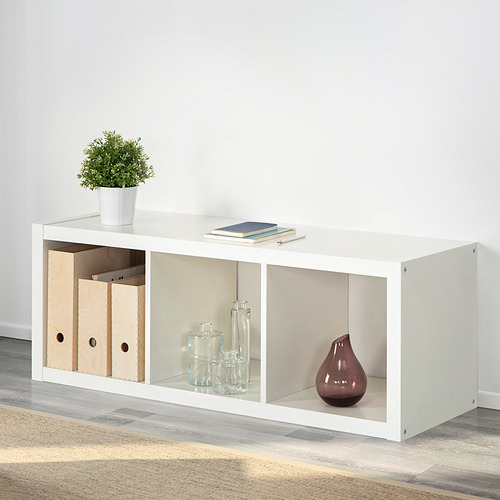 Estantería KALLAX blanca con cajas de almacenamiento y decoraciones. Muestra versatilidad y capacidad organizativa.