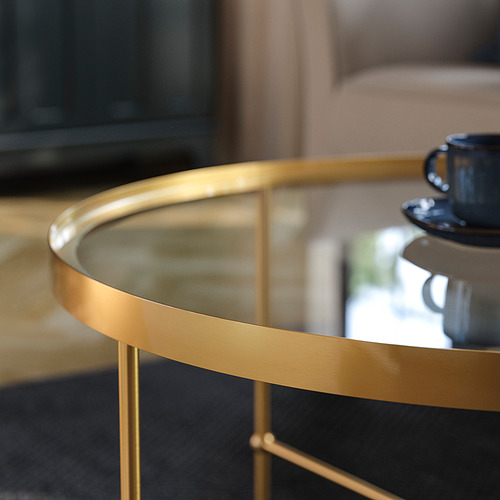 Elegante mesa de centro con marco de metal dorado y tapa de vidrio transparente, que muestra artesanía de alta calidad y diseño refinado.