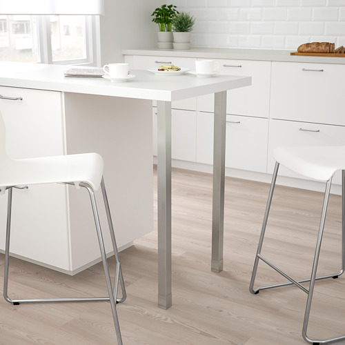 Cocina moderna con mesa y sillas UTBY blancas, patas pequeñas y metálicas, diseño simple, frente a gabinetes blancos.
