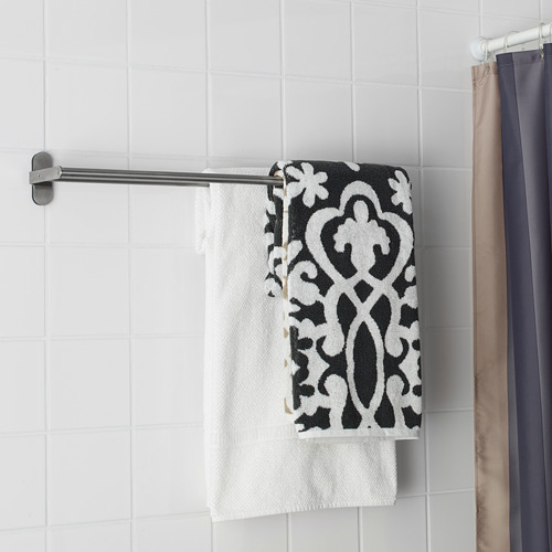 Un toallero de baño con una toalla blanca y una toalla colgante con estampados en blanco y negro. Acero inoxidable, diseño limpio y minimalista.