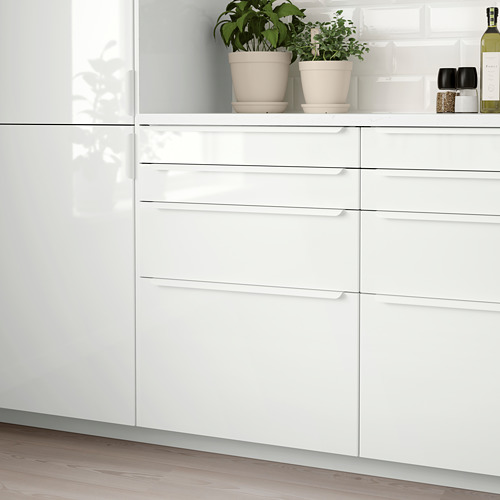 Moderno rincón de cocina blanco con cajones RINGHULT brillantes; diseño elegante y limpio; Plantas y botella en la encimera.