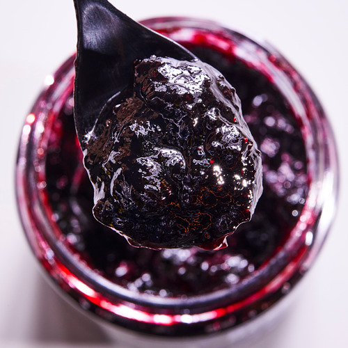 Cuchara negra con mermelada sobre el frasco.