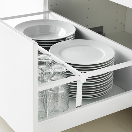 Cajón de cocina abierto que muestra platos y vasos cuidadosamente apilados, organizados con divisores para facilitar el acceso.