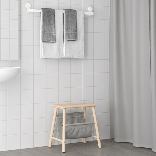 Taburete de madera, bolsa de tela, toallas, lavabo en baño minimalista.