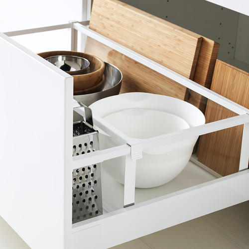 Abra el cajón de cocina METOD que muestra utensilios de cocina blancos y metálicos organizados, incluidos tazones y ralladores. El cajón tiene un mecanismo suave de cierre automático.