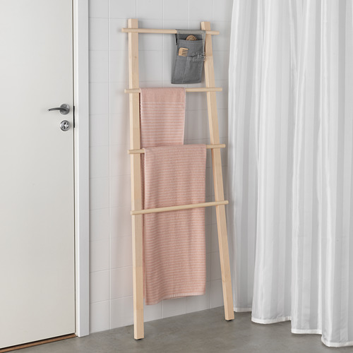 El toallero de madera de abedul sostiene toallas rosas, al lado de la puerta con manija plateada; Bolsa gris arriba para almacenamiento.