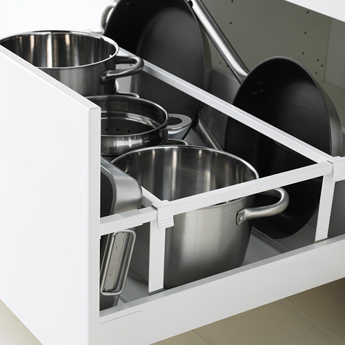 Cajón de cocina blanco abierto, con ollas de acero inoxidable y sartenes negras, mostrando un almacenamiento organizado.