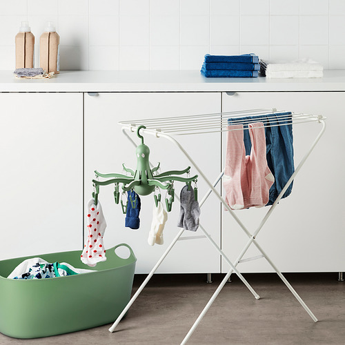 Percha PRESSA en forma de pulpo, de color blanco, sujeta ropa y calcetines. Se sienta en el estante, cabe cerca de la canasta verde.