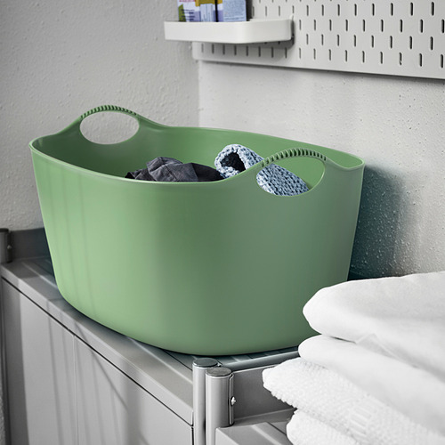 Cesta de lavandería TORKIS verde en estante con toallas.