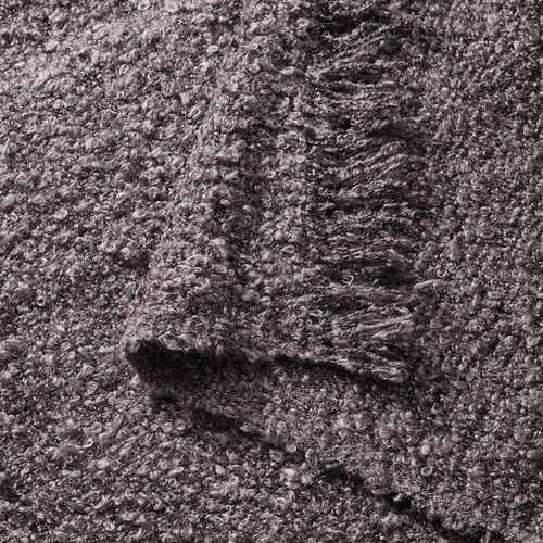 Primer plano de una acogedora manta de punto arrugado gris con bordes suaves con flecos.