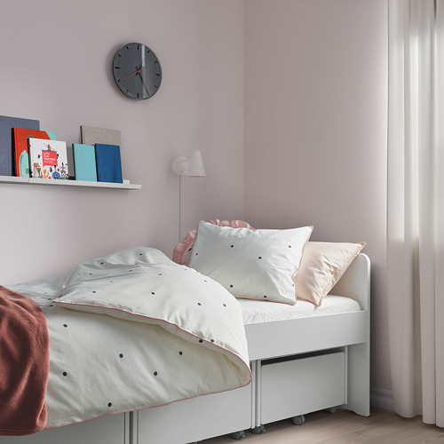 Dormitorio infantil con cama blanca, edredón de puntos negros, detalles en rosa, decoración ordenada.