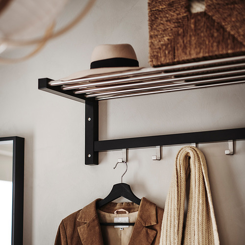 Perchero de madera negra con chaqueta colgante, sombrero y bufanda.