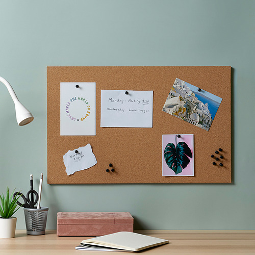 Tablero de corcho FLÖNSA con alfileres, pared verde, escritorio con notas, planta, lámpara, portalápices.