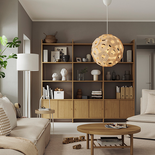 Salón moderno con muebles ligeros, luz central, decoración en estanterías, planta grande.