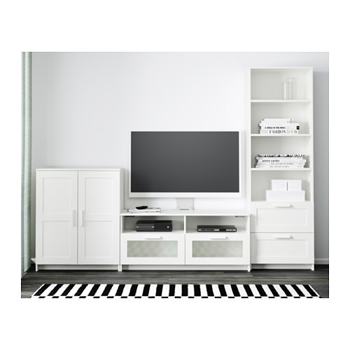 Sala de estar moderna con muebles blancos: televisor en soporte, cajones de almacenamiento, estantes ajustables y administración de cables. Alfombra de rayas blancas y negras.