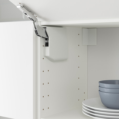 Se muestra un gabinete de cocina blanco con mecanismo de elevación de la puerta de vértiga, que incluye pestillo para un cierre suave. Cuencos y platos apilados en el estante.