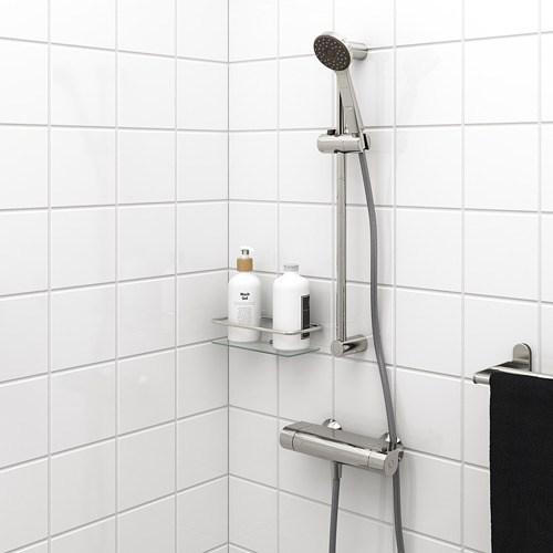 VALLAMOSSE: rociador y barra de ducha cromados. Auricular de rociado completo en riel. Botellas pequeñas cerca. Ducha de pared con azulejos blancos.