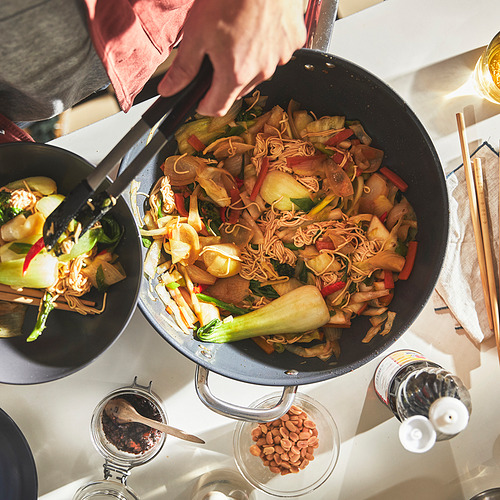 Un wok antiadherente sirve fideos salteados y verduras, fácil de limpiar.