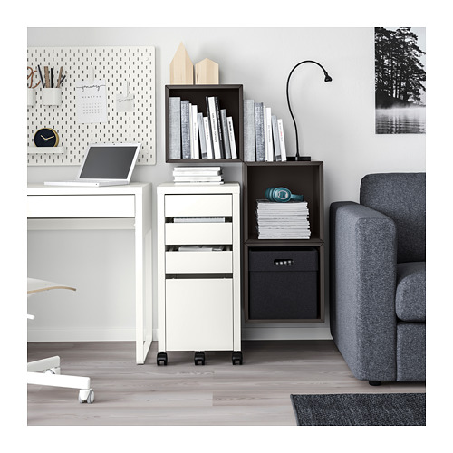 Moderna configuración de oficina con unidades de almacenamiento EKET blancas, que contienen libros y archivos. Escritorios minimalistas y sofá tapizado en gris.