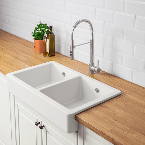 Fregadero de cocina moderno con grifo abatible. Lavabo doble para un lavado y preparación eficiente de la vajilla, colocado en encimera de madera rústica.