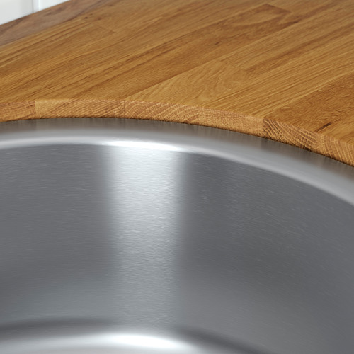 Un fregadero de acero inoxidable con un interior pulido y reflectante y un borde elegante, que se encuentra con una encimera de madera.