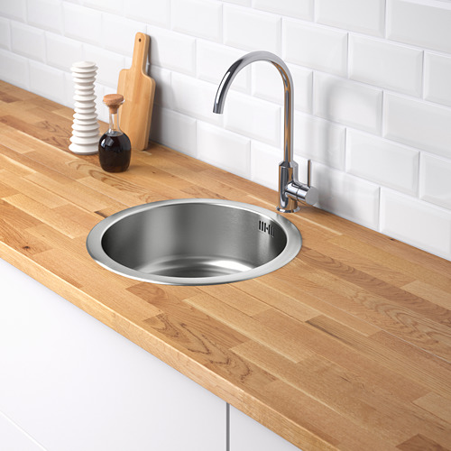 Un fregadero de cocina moderno con un grifo curvo, ubicado en una encimera de madera contra una pared de ladrillo blanco.