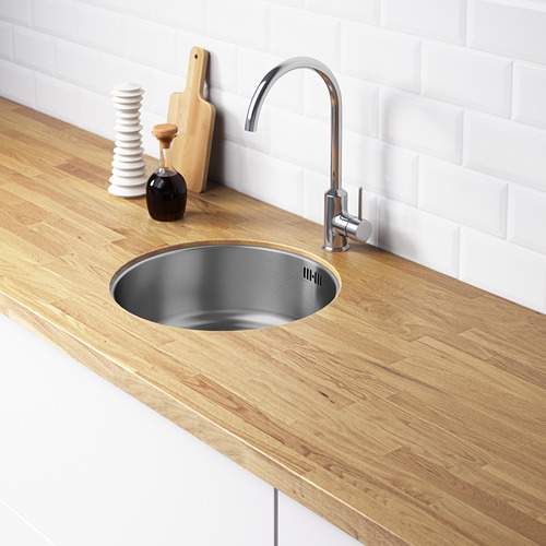 Fregadero de cocina moderno con grifo de plata sobre encimera de madera, fregadero de acero inoxidable, elementos decorativos, salpicadero blanco.
