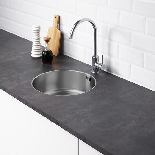 Fregadero de cocina moderno con grifo elegante y encimera oscura sobre azulejos blancos.