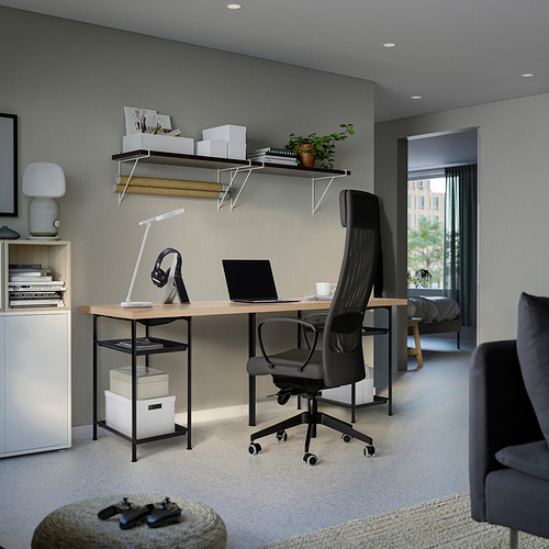 Moderna oficina en casa con escritorio, silla, computadora portátil, lámpara, auriculares, libros, plantas, gabinete, sofá.