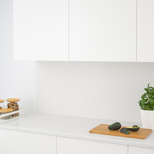 Encimera de cocina moderna con un protector contra salpicaduras de cuarzo, que muestra aguacates en una tabla de cortar.