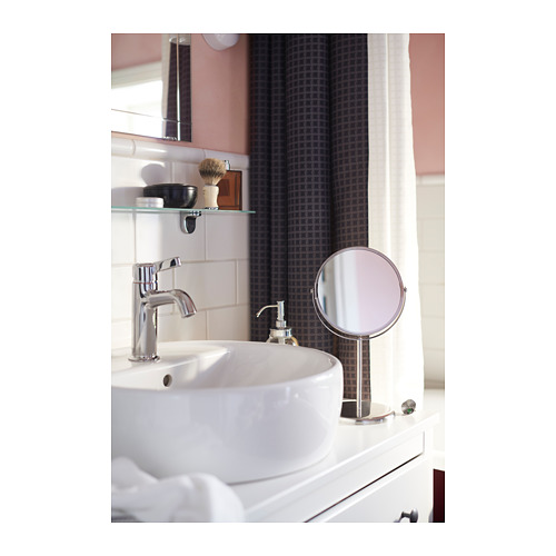 Lavabo de baño con grifo cromado, dispensador de jabón y espejo de tocador. Encimera blanca, cortina gris.