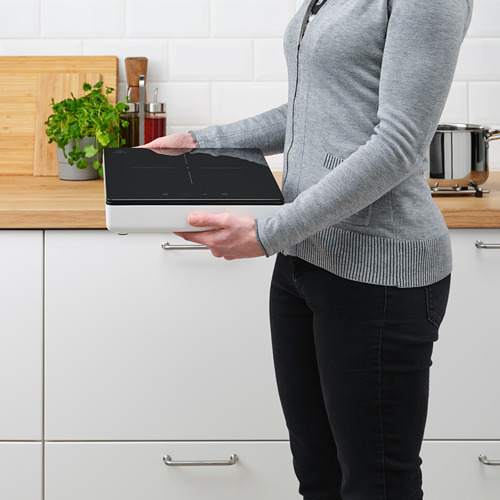 Persona utilizando una placa de inducción portátil en la cocina.